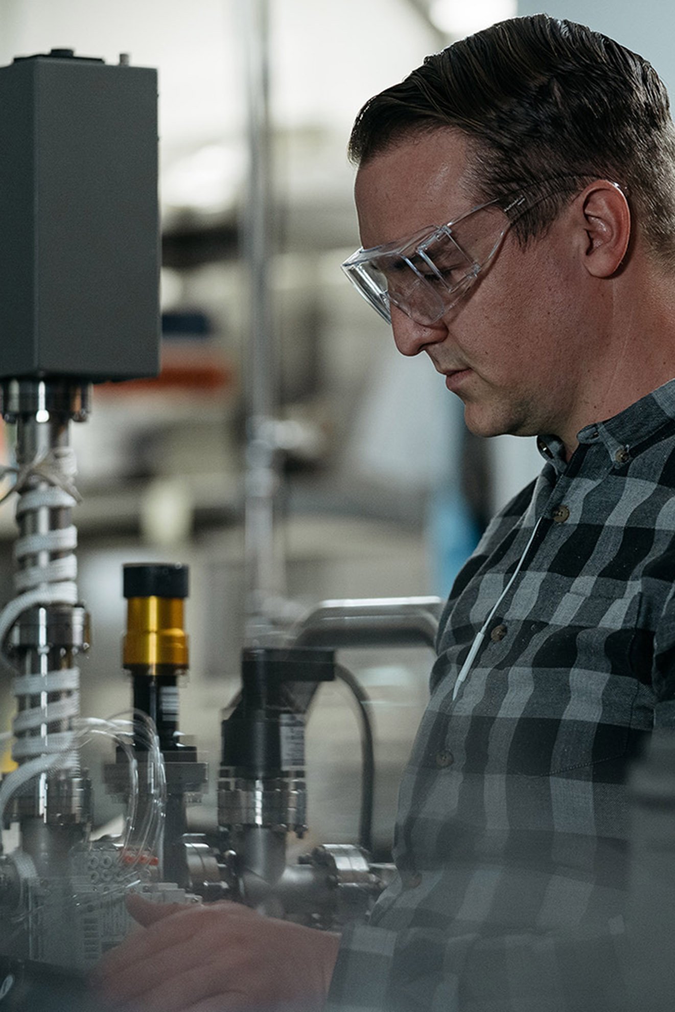An ASML staff member in safety glasses works on a computer surrounded by machines. An ASML staff member in safety glasses works on a computer surrounded by machines.