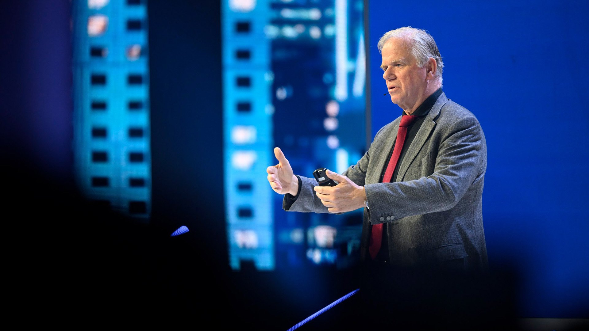 Man gesturing while speaking on a stage Man gesturing while speaking on a stage