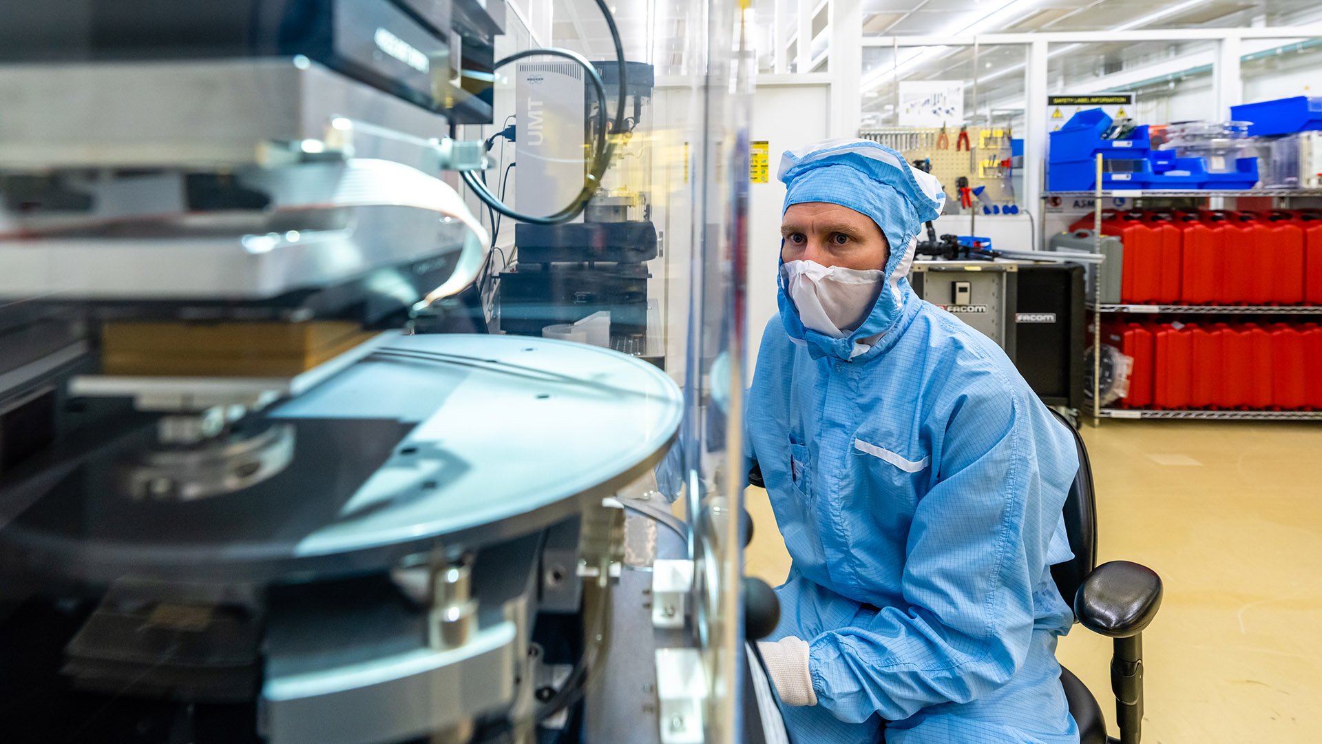 Person in protective clothing observing a lithography machine Person in protective clothing observing a lithography machine